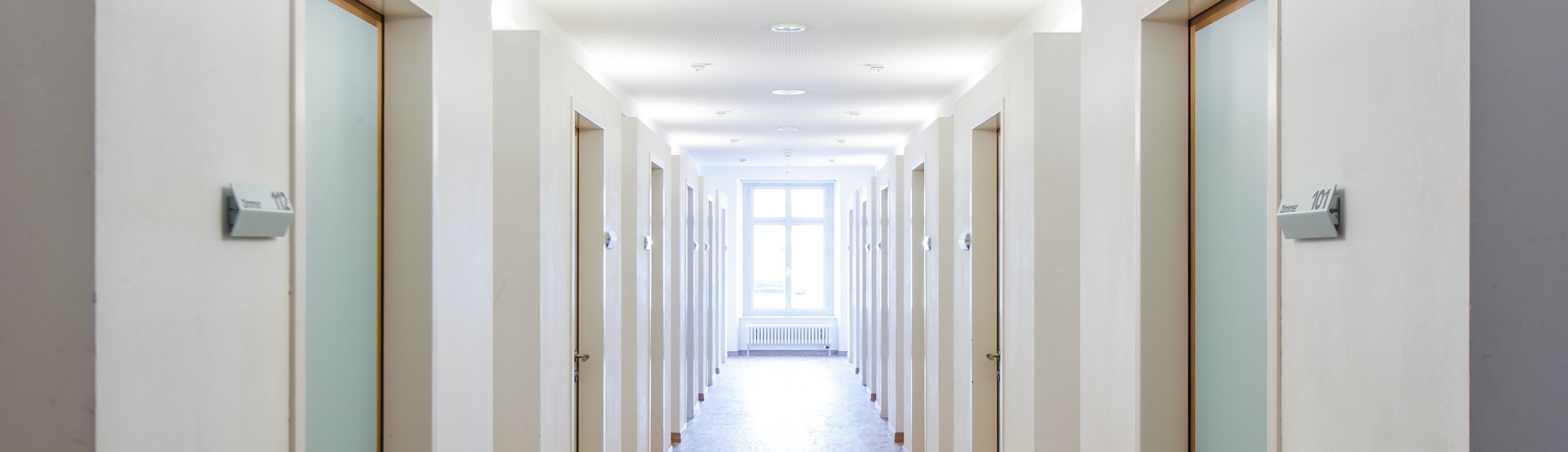 A hallway with many doors in a dormitory or hotel