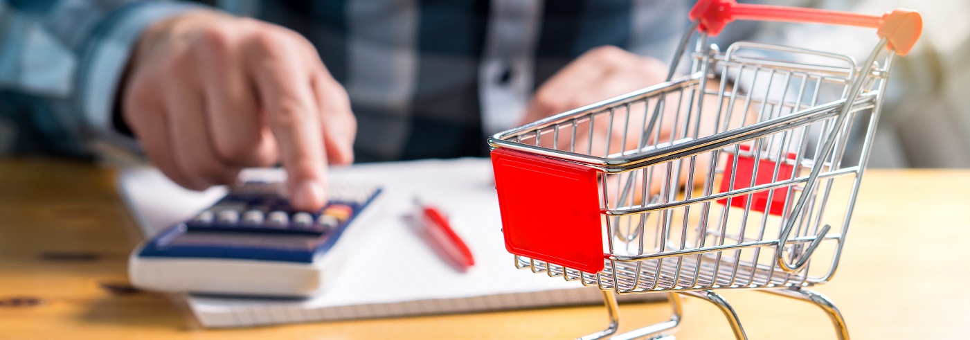 Miniature grocery cart with a person working on a calculator in the background